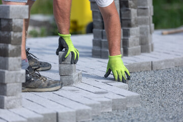 Worker doing new interlocking paving sidewalk made from concrete blocks