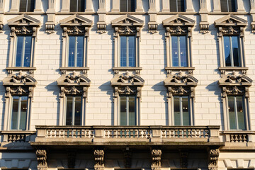detailed neoclassical facade of a building adorned with intricate stone carvings and sculpted figures, under soft sunlight