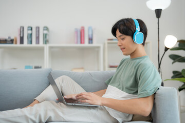 Young adult enjoying music and working on laptop at home