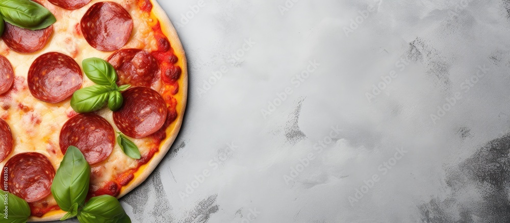 Poster a top down view of a pepperoni pizza with a close up of fresh basil on a light concrete or stone tab