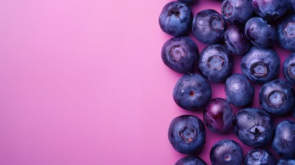 A vibrant image featuring fresh, juicy blueberries arranged on a clean, pink surface, with water droplets visible on the fruit