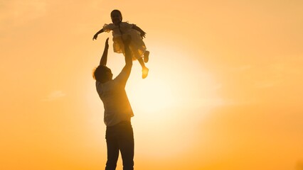 father throws child kid daughter into sky, silhouette happy family, children dream flying airplane pilot, daughter in sunset, loving playtime, daddy lifting daughter, sunny happiness, child high in