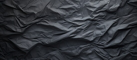 A crumpled piece of dark grey paper creates a textured background perfect for showcasing a copy...