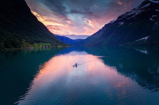 Fiery Sunset Aerial: Kayaker Gliding in Full Reflections on Norwegian Fjord