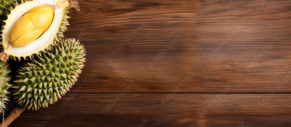 Poster Copy space image of a ripe durian fruit with thorns on a wooden board background perfect for adding text