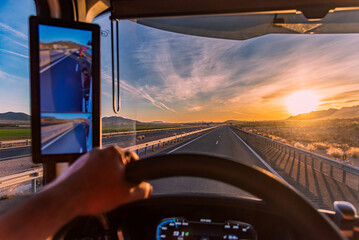 View from inside the cabin of a truck of a straight highway and a sunrise with the sun on the...