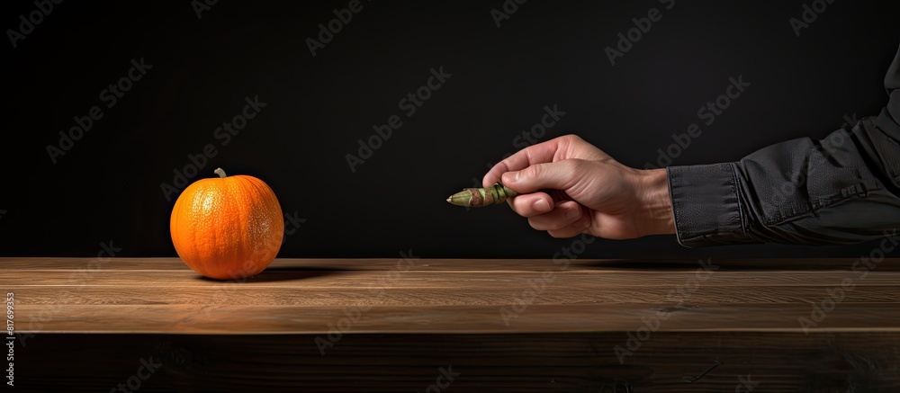 Aufkleber a man places a small orange pumpkin on a walnut table creating a wide photo with ample copy space