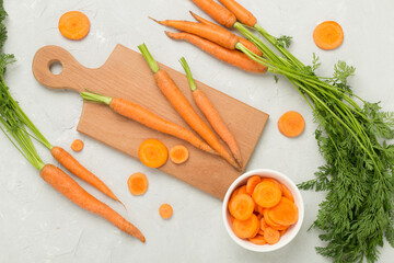 Bunch of fresh carrots with sliced ones on concrete background, top view