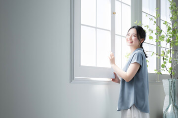 Woman standing at window looking up toward the outside Image of relaxing and waking up early in the...