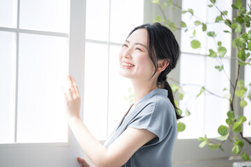 Woman standing at window looking up toward the outside Image of relaxing and waking up early in the...