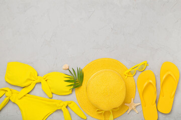 Flat lay with yellow summer outfit on concrete background. Vacation concept