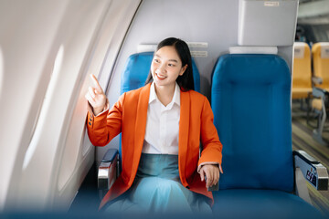 Asian executive excels in first class, multitasking with digital tablet, and smartphone. Travel in...