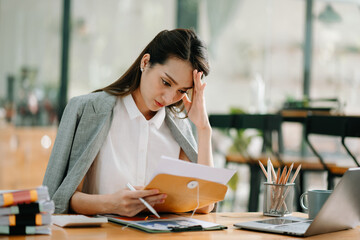 Asian Businesswoman Analyzing Finance on Tablet and Laptop at modern Office Desk tax