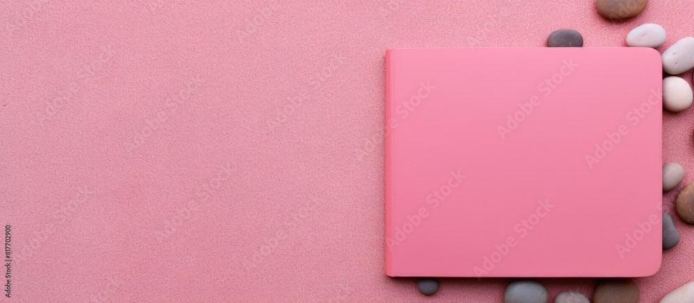 Leinwandbilder A pink background with a pebble on it serves as a colorful surface for a top view of a blank notebook with ample copy space