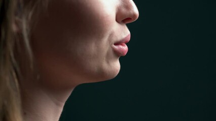 side view of beautiful young woman speaking to the camera, showing white straight healthy teeth. beautiful lips smile and move when the lady gives a speech