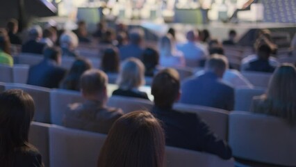 An audience of engaged professionals listens intently at a conference presentation, capturing the essence of business learning and networking in a corporate environment.