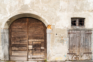 large old wooden doors set in weathered stone archway with crumbling facade