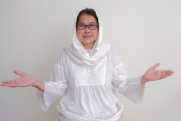 A woman wearing a white hijab is opening her arms; smiling