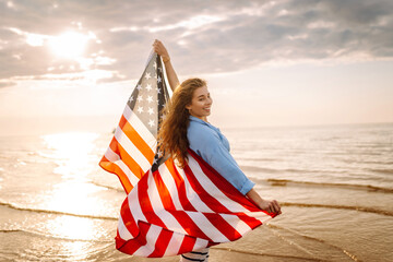 Young woman holding national American flag cover ocean beach holiday travel at summer romantic...