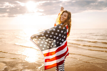 Young woman holding national American flag cover ocean beach holiday travel at summer romantic...