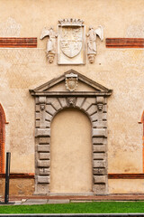 detailed coat of arms flanked by statues on a weathered facade, enhancing the historic character of the architecture