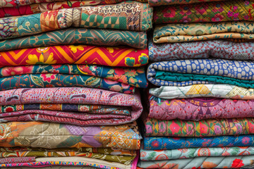 A stack of colorful quilts, with different fabric patterns and textures.