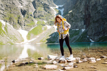 Active woman enjoys the beautiful scenery of the majestic mountains and lake. Travel, adventure. Active life.