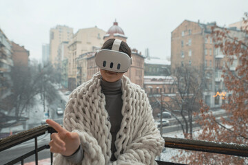 Enjoying VR experiences, a young lady dons a headset on the winter balcony.