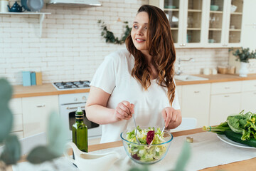 Lifestyle moments of a young woman at home. Woman enjoying a salad and healthy food in the kitchen.