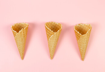 Top view of three ice cream waffle cones on pink background. Summer wallpaper, flat lay, copy space.