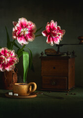 A cup of hot, aromatic coffee, an old coffee grinder and a bouquet of peony tulips. Still life.