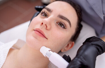 Fototapeta premium Young beautiful woman getting lifting anti-aging, face massage a