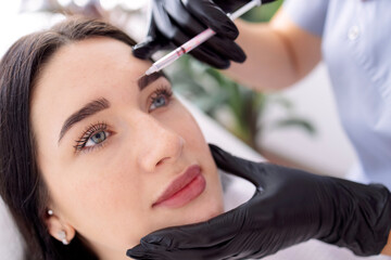 Obraz premium Beauty injections. Female cosmetologist in black gloves makes an injection
