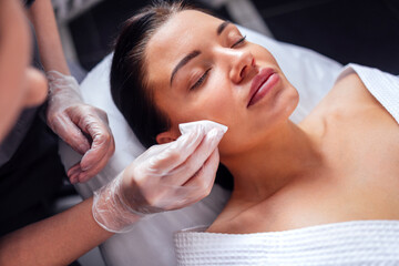 Young brunette girl during facial cleansing procedure in beauty salon