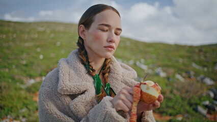 Woman peeling apple fruit on outdoor journey. Closeup mountain traveler snack