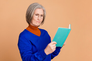 Photo portrait of attractive retired woman read minded book dressed stylish blue clothes isolated on beige color background