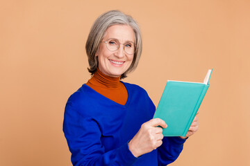 Photo portrait of lovely pensioner lady hold read book dressed stylish blue garment isolated on beige color background
