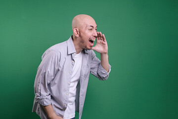 Side view of bald man shouting and cupping hands around mouth