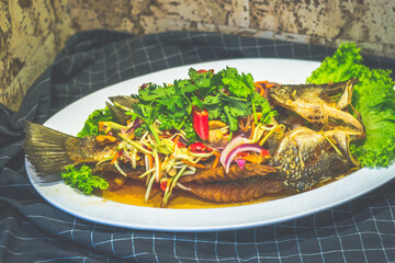 Deep Fried Seabass topeed With Mango Salad and served on a plate