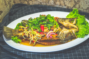 Deep Fried Seabass topeed With Mango Salad and served on a plate