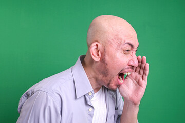 Side view of bald man shouting and cupping hands around mouth