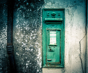 a mail box on the side of a stone wall with a rusted metal handle