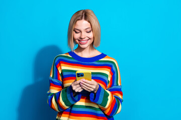 Portrait of pretty young girl use smart phone empty space wear striped pullover isolated on blue...