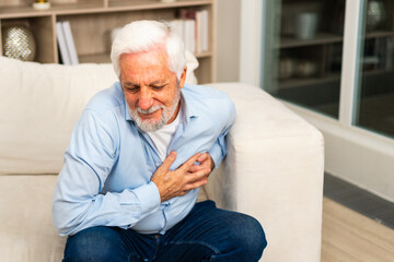 Pain on heart, heart attack. Unhappy middle aged senior man suffering from chest pain heart attack problems with health at home. Mature old senior grandfather touching chest experiencing infarction