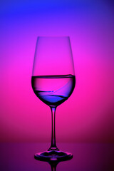 Crystal clear glass of liquid against a vibrant, neon pink background