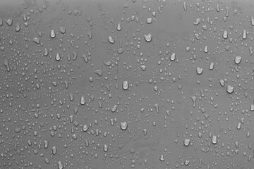 Droplets of water cascading down a reflective metal wall.