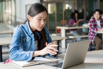 Asian woman female student excited checking language test results on laptop. Smile girl happy study online. book in college campus. Portrait female on international Asia University. Education