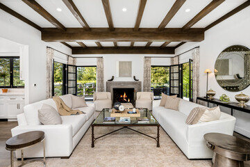 Modern living room with two white couches positioned in front of a fireplace and large windows