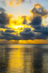 Scenic view of golden sunset over a tranquil sea on a cloudy day