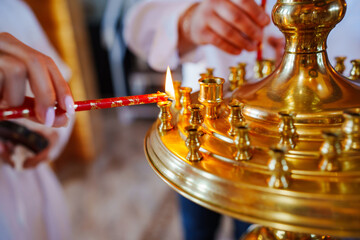hands lighting candle from candles burn in a candlestick in the church. the tranquility and beauty of the church service.